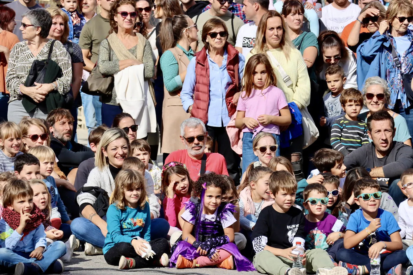 Canalla asseguda a terra mirant un espectacle